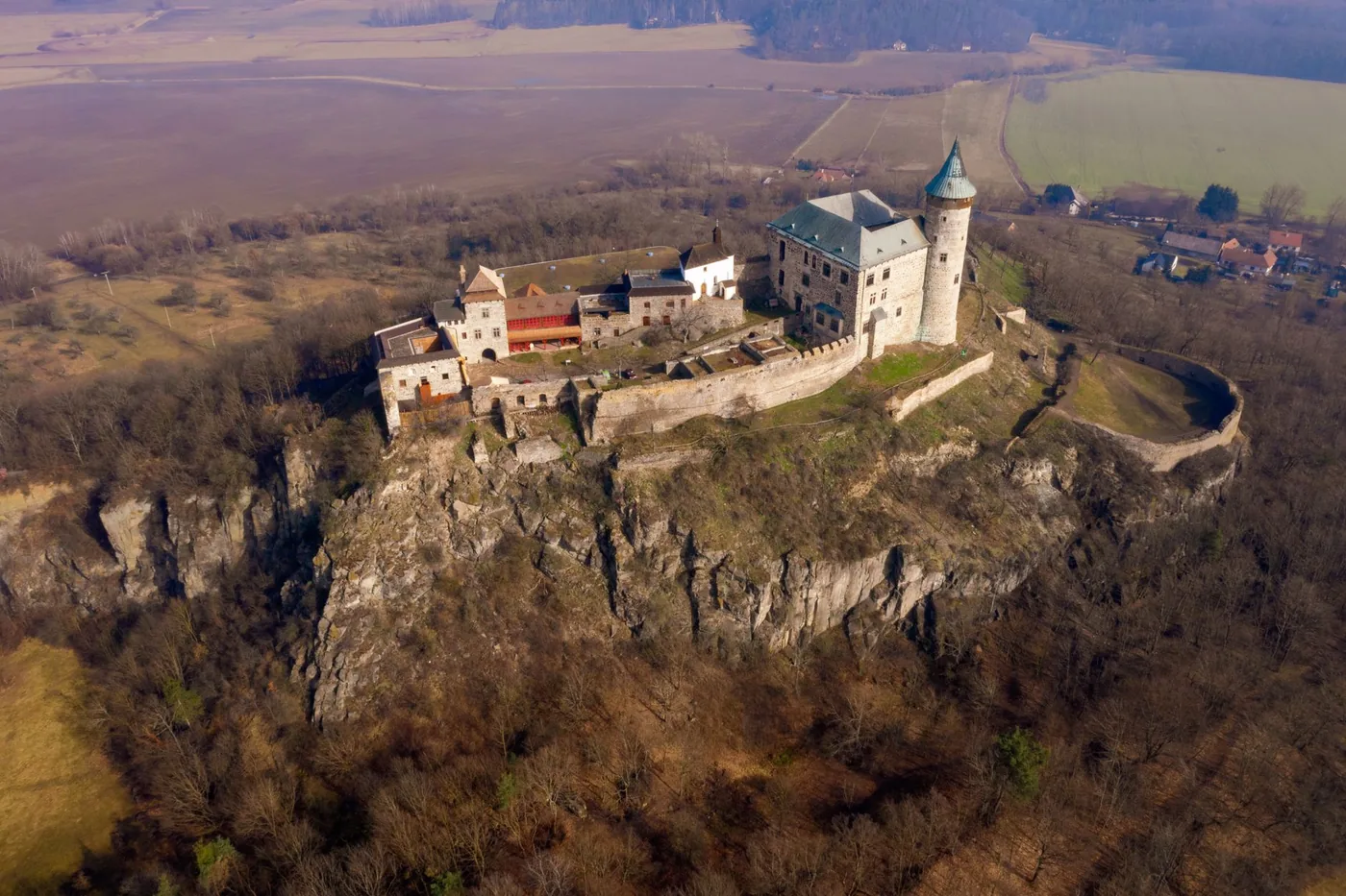 Středověký hrad na kopci obklopený lesem, typický pohled na region Středních Čech